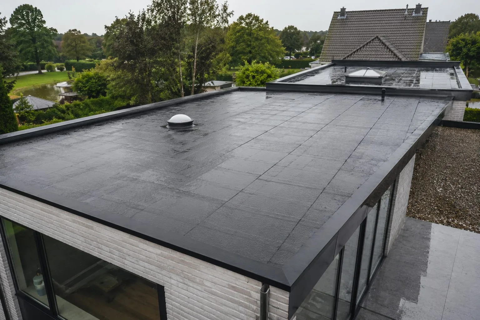 Plat dak met EPDM in een stuk gelegd, strakke dakranden en een lichtkoepel