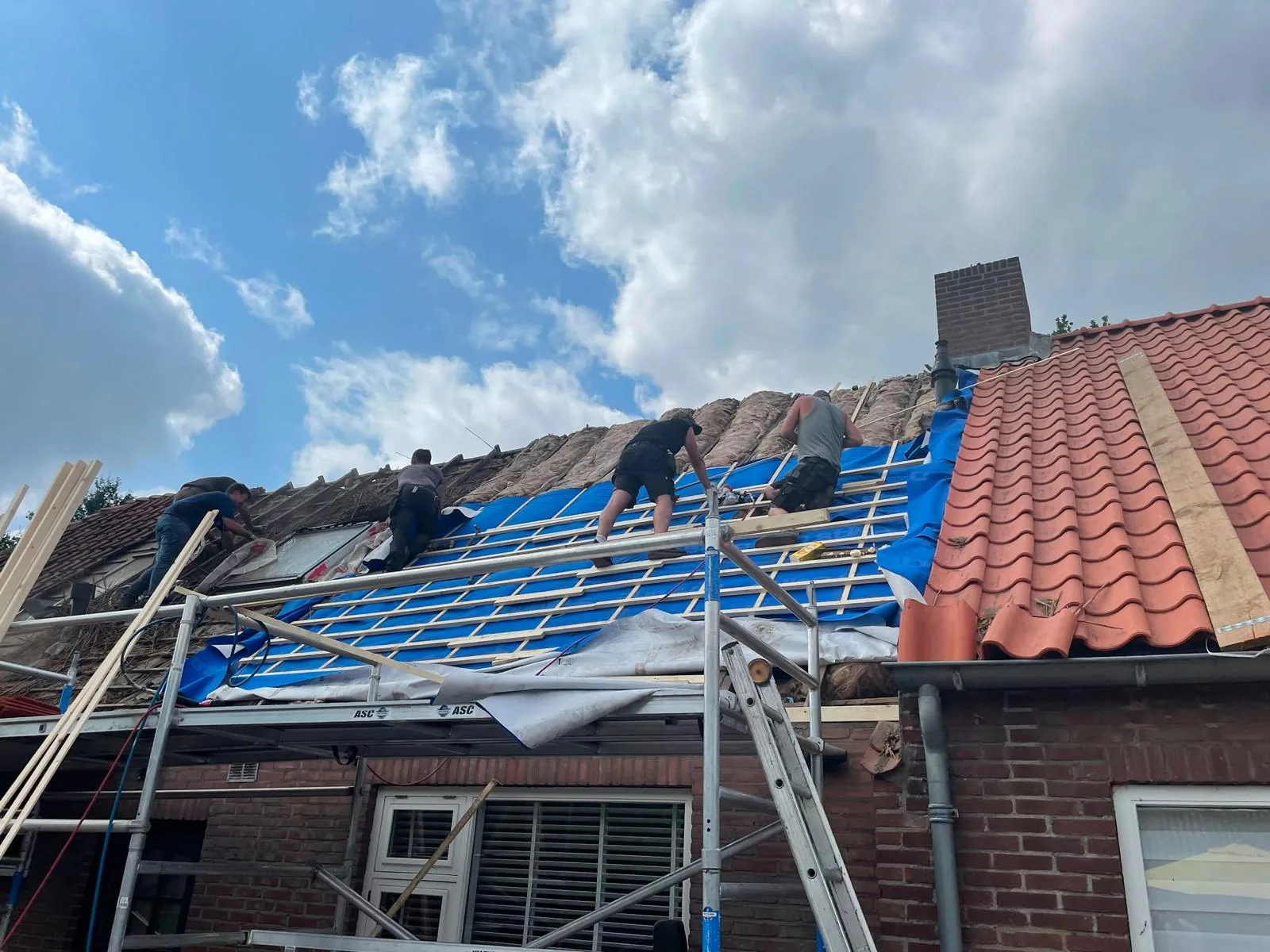 Dakdekkers van Boers & Breuer bezig op een schuin dak met nieuwe panlatten en dakpannen