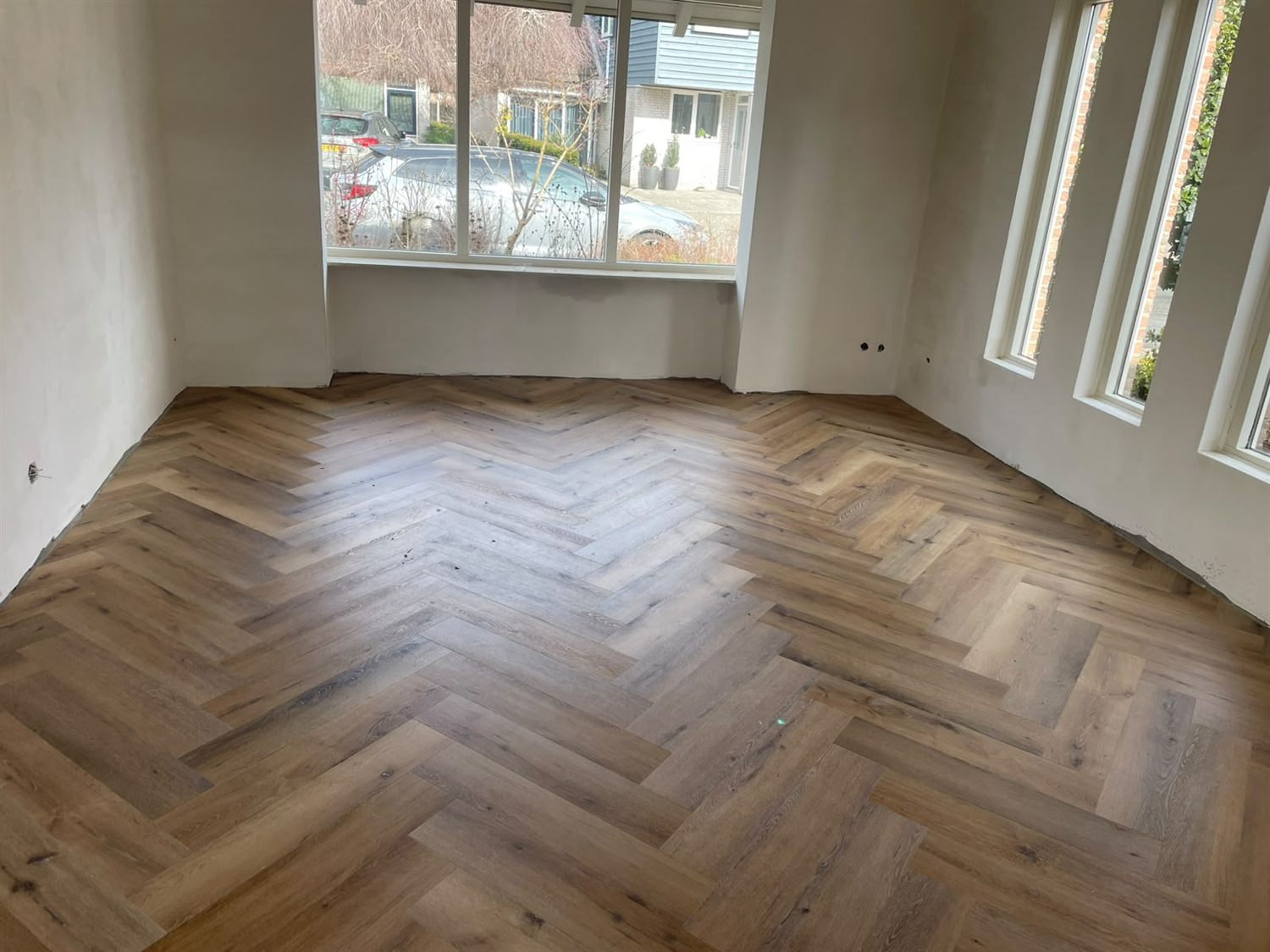 Woonkamer met een nieuw gelegde visgraatvloer in een rustiek eikenpatroon