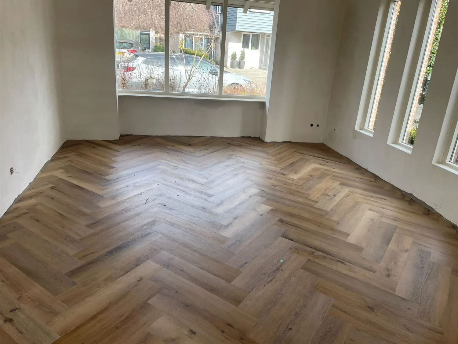 Woonkamer met een nieuw gelegde visgraatvloer in een rustiek eikenpatroon